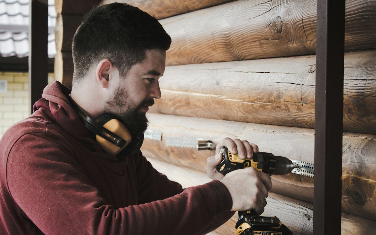 Carpenter wearing ear protection driving a screw with a cordless drill